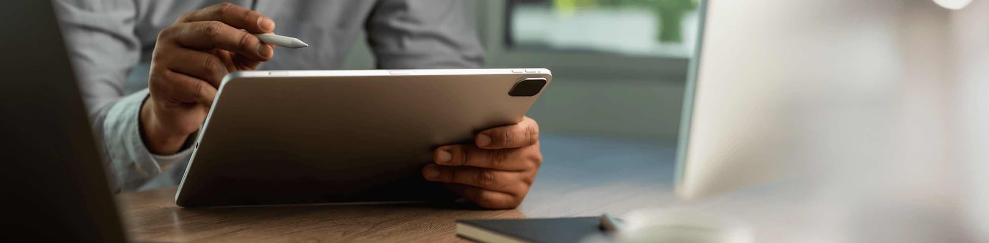 Close up of hands holding a tablet and a stylus. Simple and quick access to information is essential for business transformation.