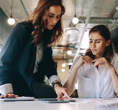 A businesswoman showing a colleague something on a tablet.