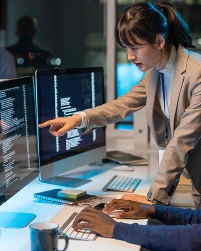 A businesswoman points at a screen with data and coding points on it.