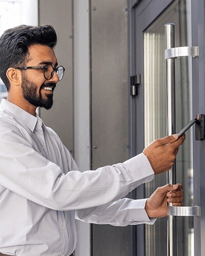 A young man taps his phone to a unlock a door.